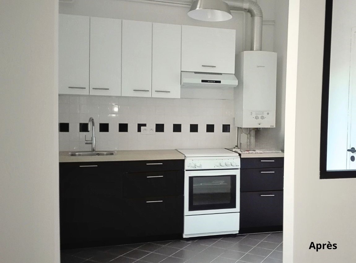 Cuisine noire et blanche avec une vue sur la verrière noire entre elle et la salle de vie . Enfilade de pièce. Appartement blanc avec les boiseries noires.